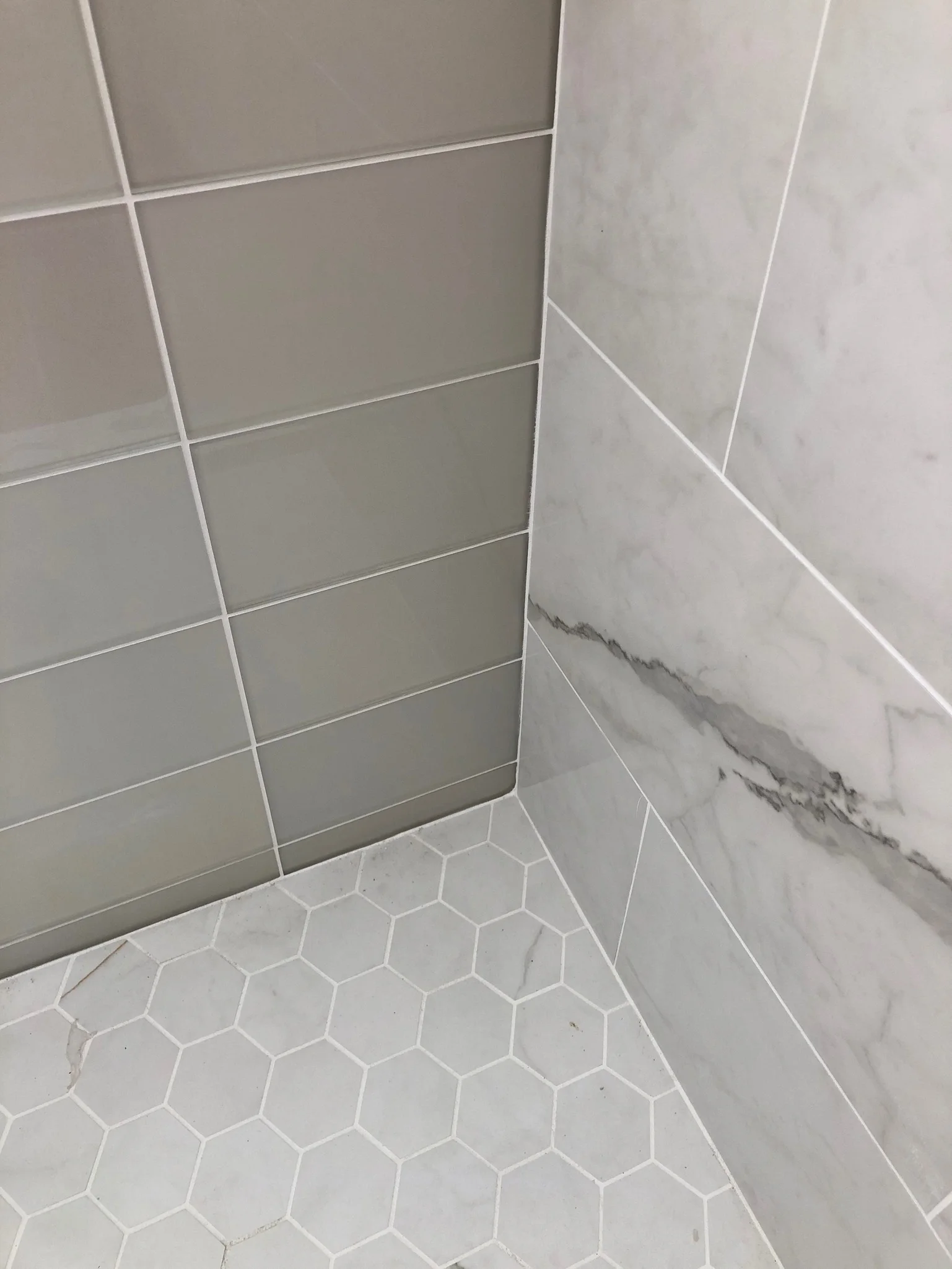 Gray and white shower tile with a hexagonal mosaic floor