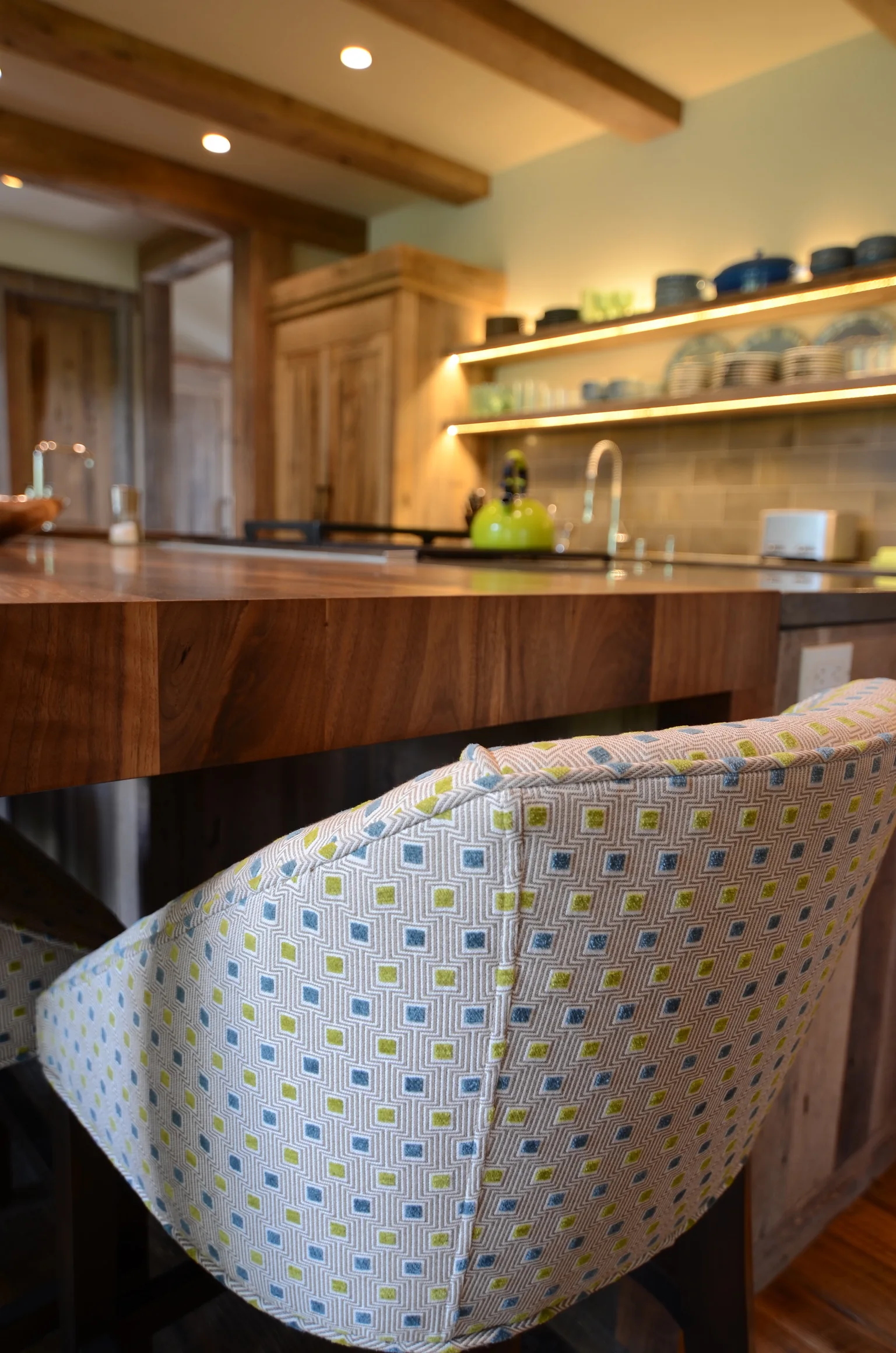 Patterned upholstered chair beside a warm wood kitchen island