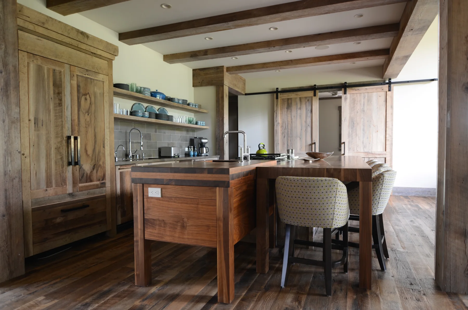 Warm wood kitchen with exposed ceiling beams and upholstered stools