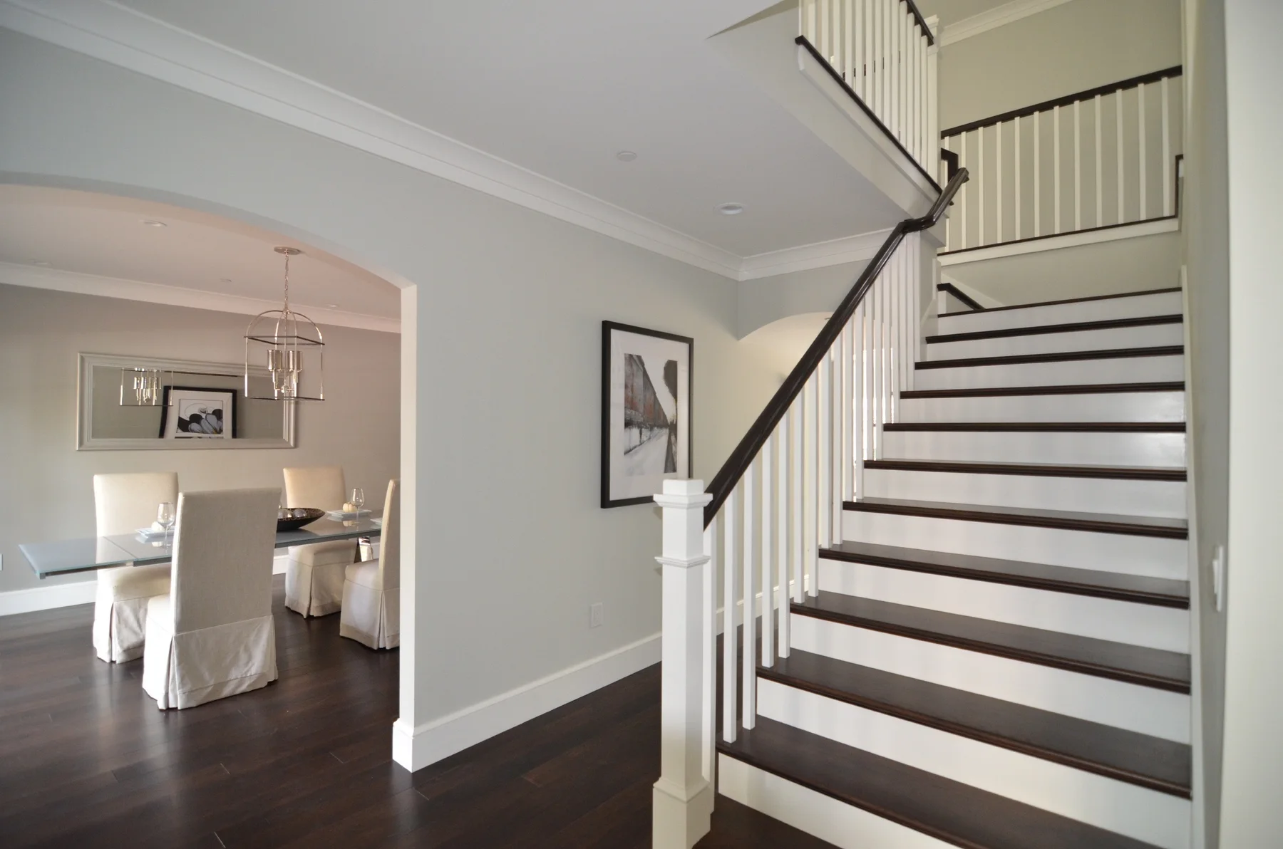 Bright entry staircase with dark wood handrail and floors