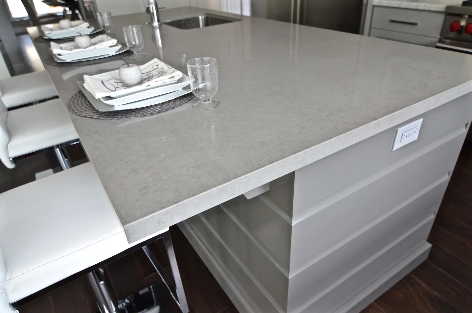 Gray kitchen island with a textured stone counter and place settings