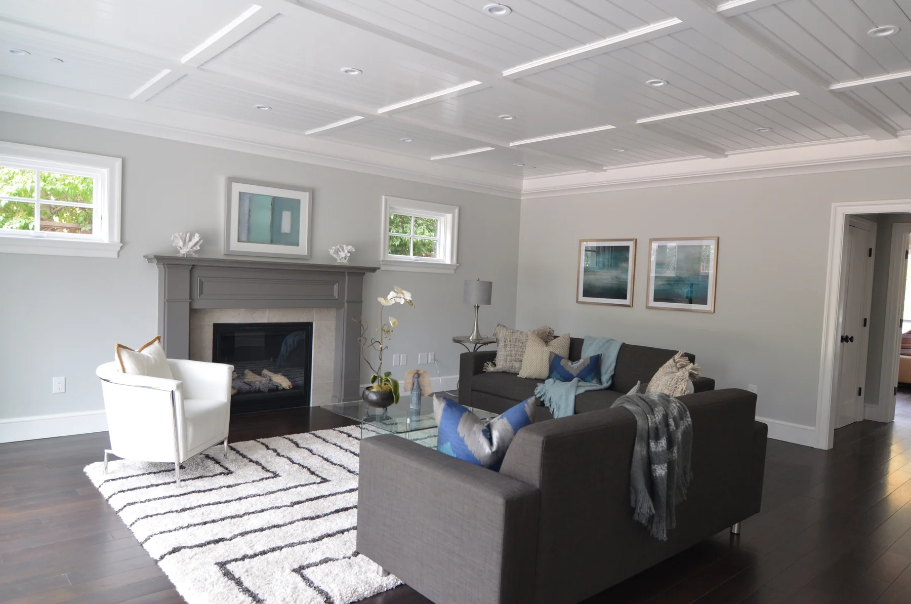 Gray living room with a coffered ceiling, fireplace, and patterned rug