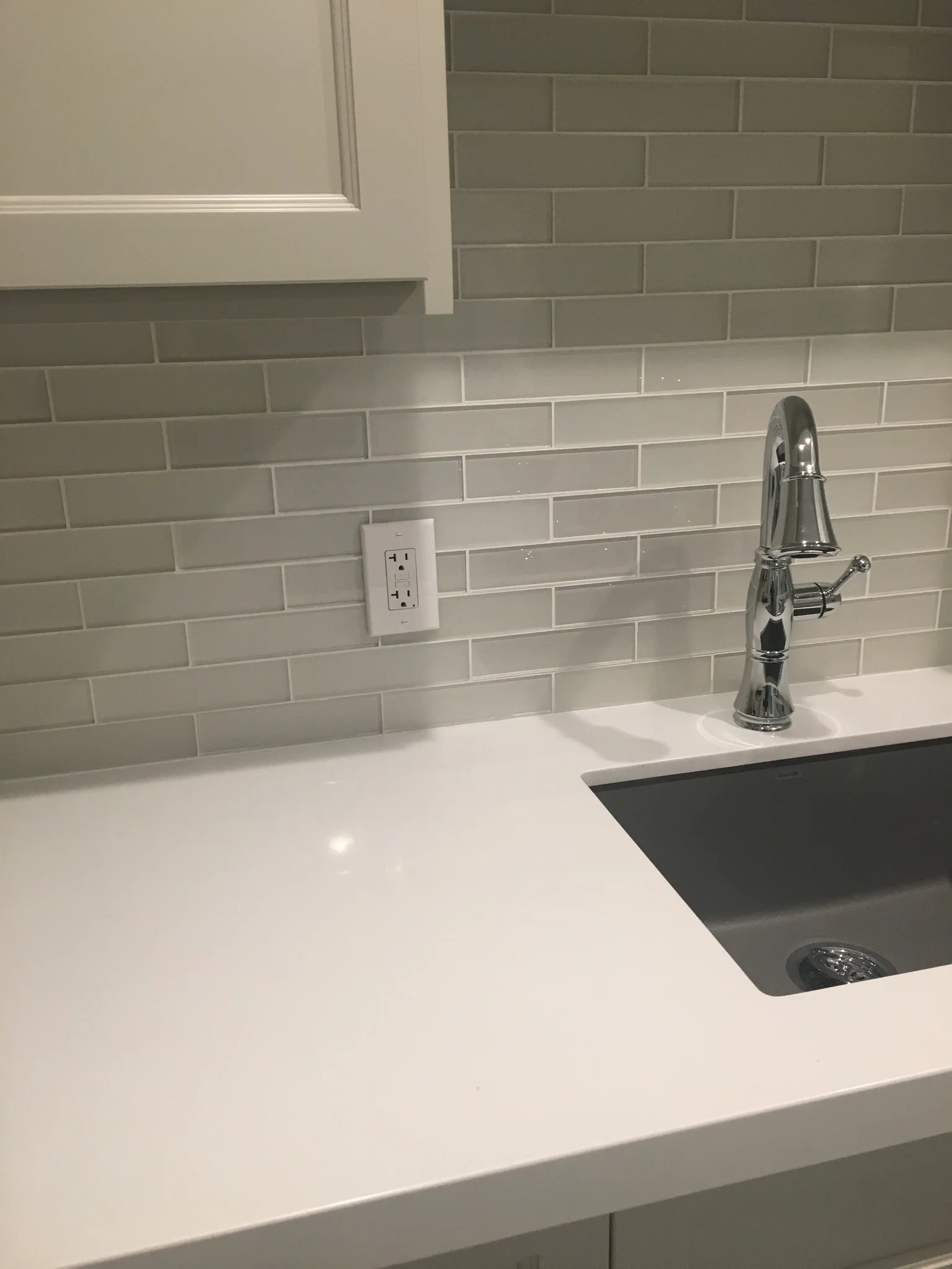 White kitchen sink with glossy gray subway tile backsplash